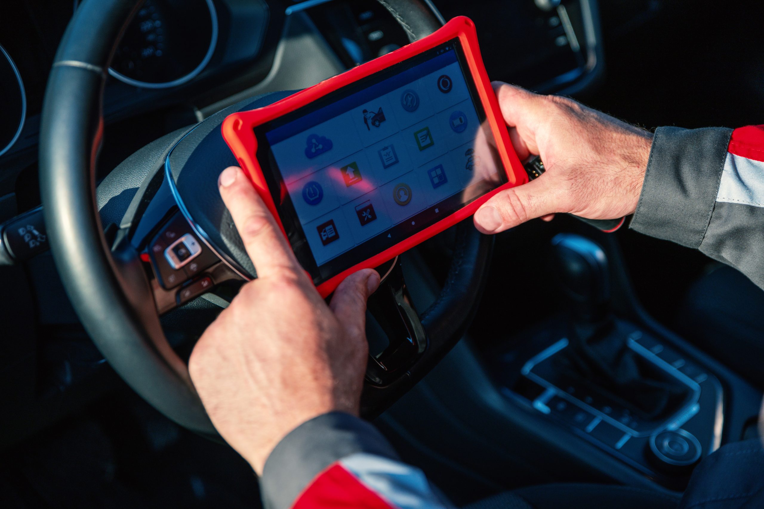 Car mechanic holds tablet for checking the electronic systems of cars