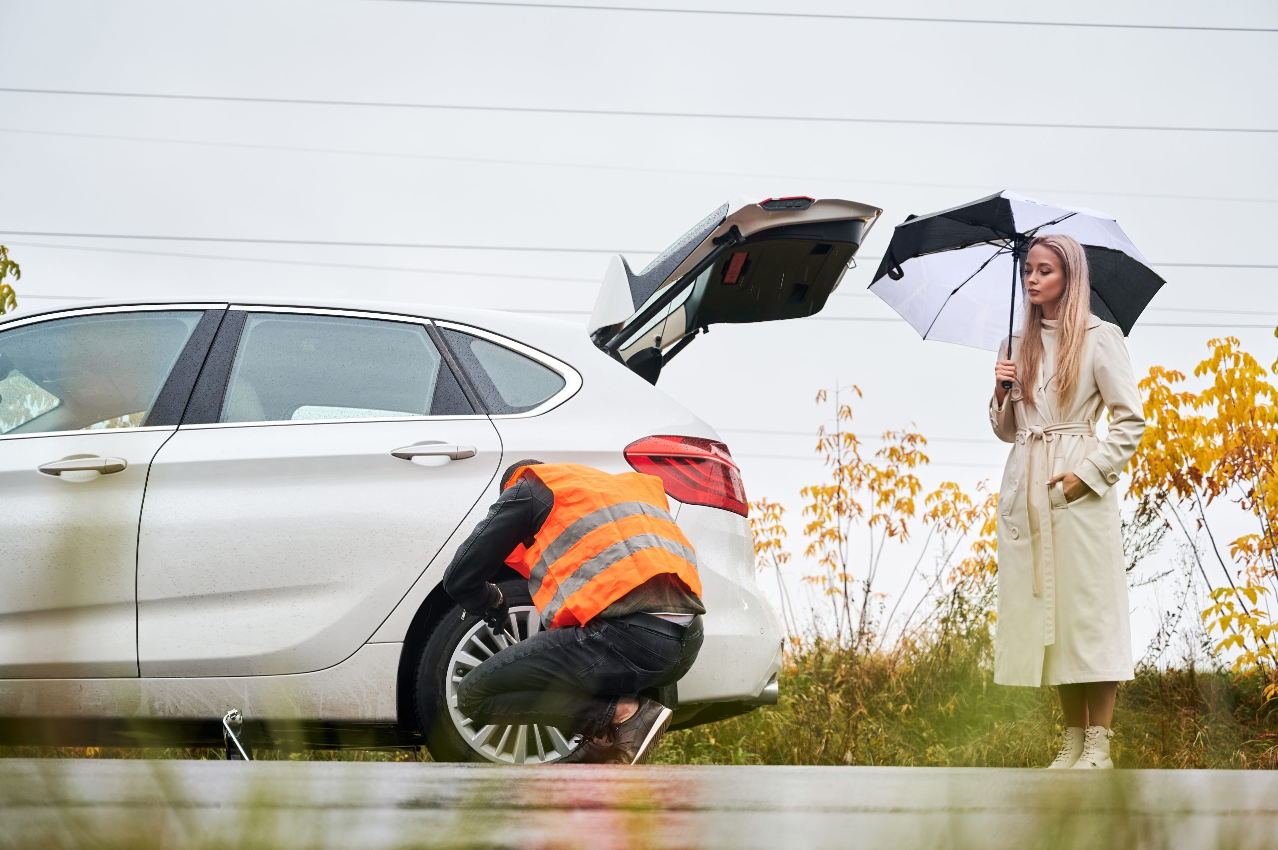 Emergency mechanic repairing young woman vehicle on the street.
