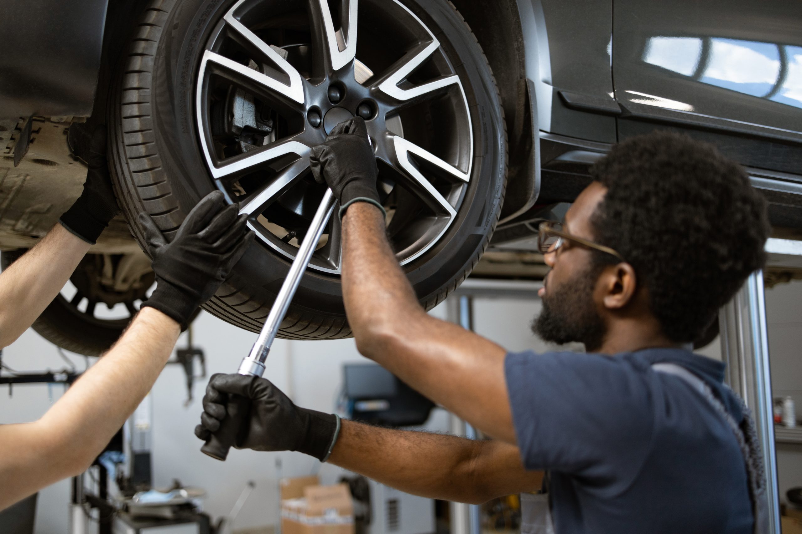 Mechanics working on car wheel in auto repair shop