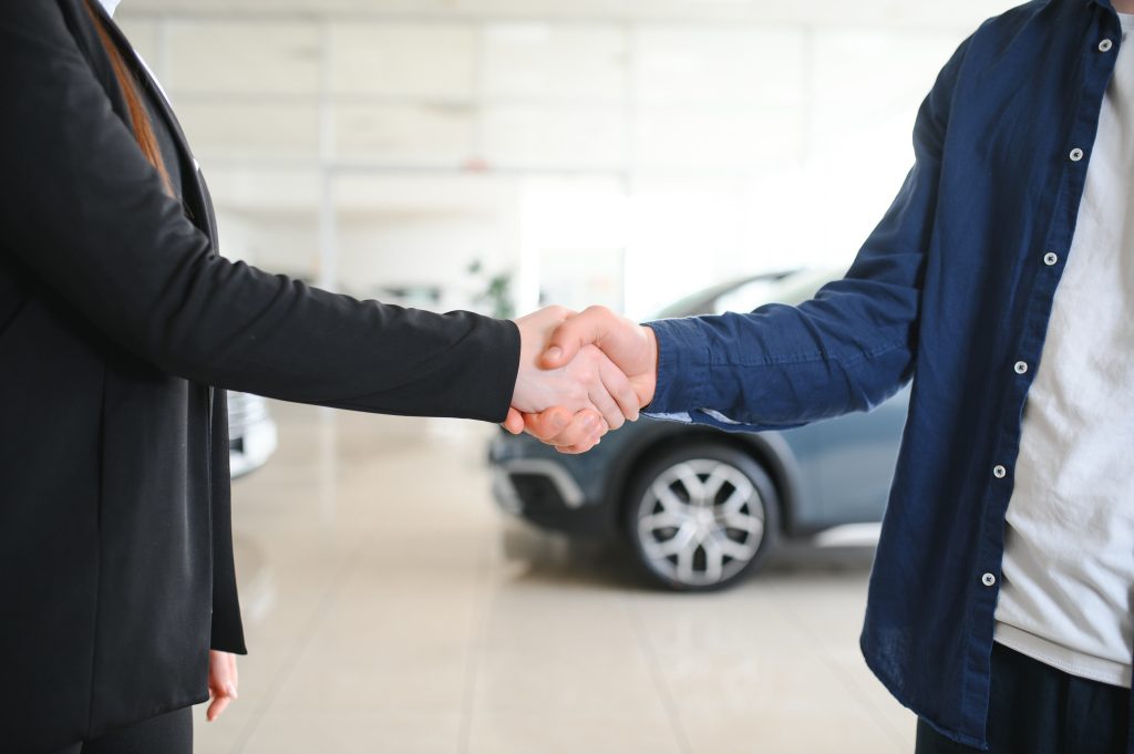 Woman shaking hands with car salesperson