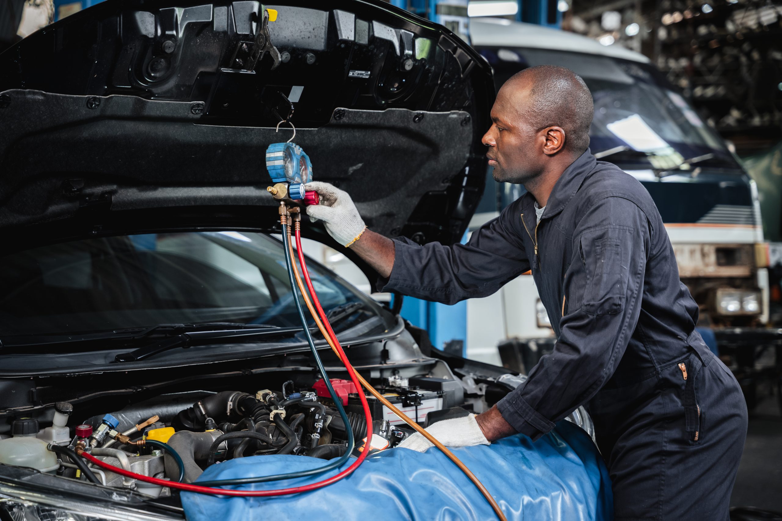 In the garage, mechanics examine and inspect the refrigerant before filling the car's air conditioner with it.