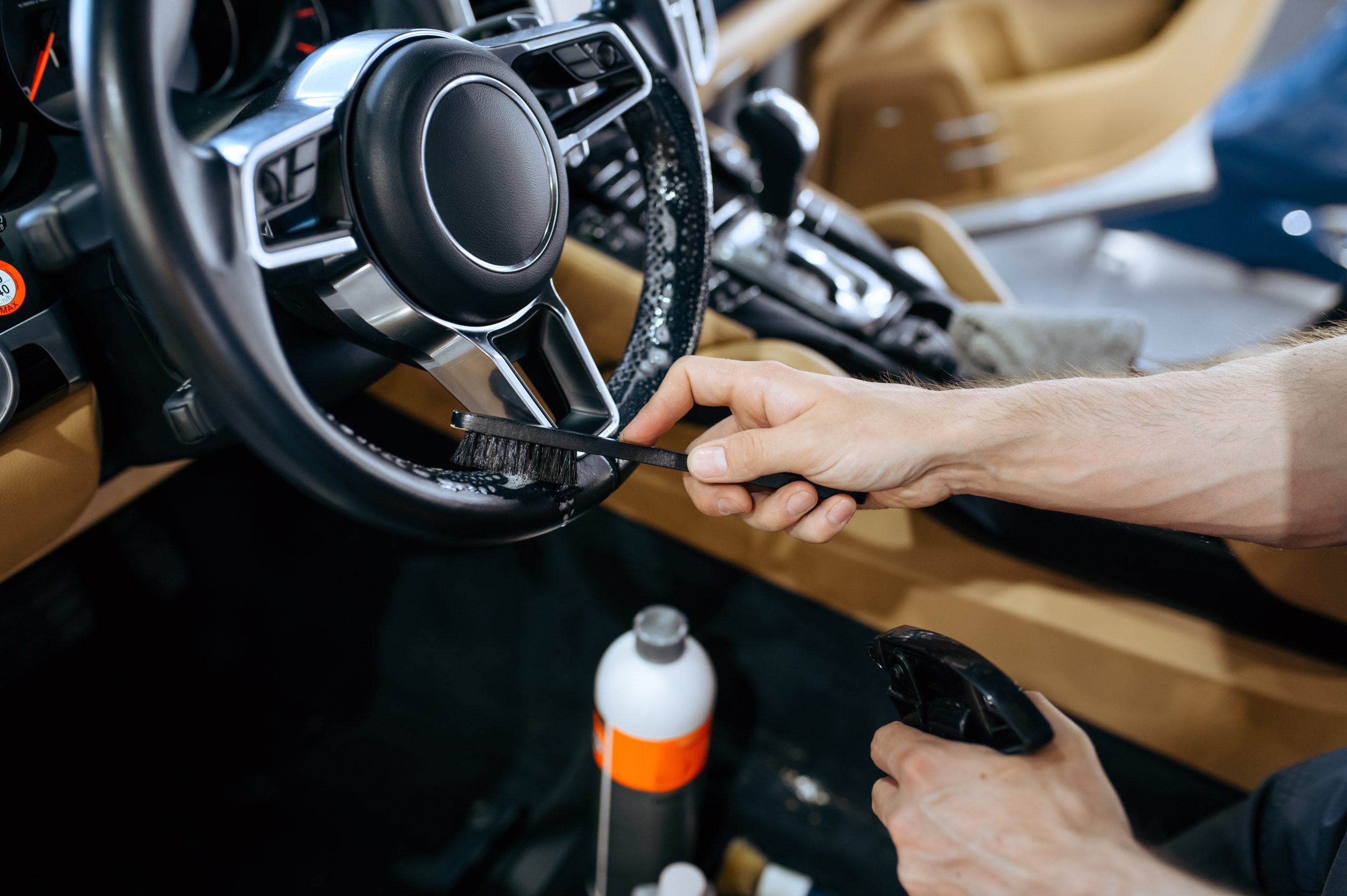 Worker wipes car steering wheel, detailing
